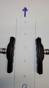 Et eksempel på bremseklodser der er monteret med den rigtige vinkel i forhold til fælgen. (Pilen indikere hvilken vej fælgen drejer).