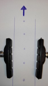 Et eksempel på bremseklodser der er monteret med den forkerte vinkel i forhold til fælgen. (Pilen indikere hvilken vej fælgen drejer).